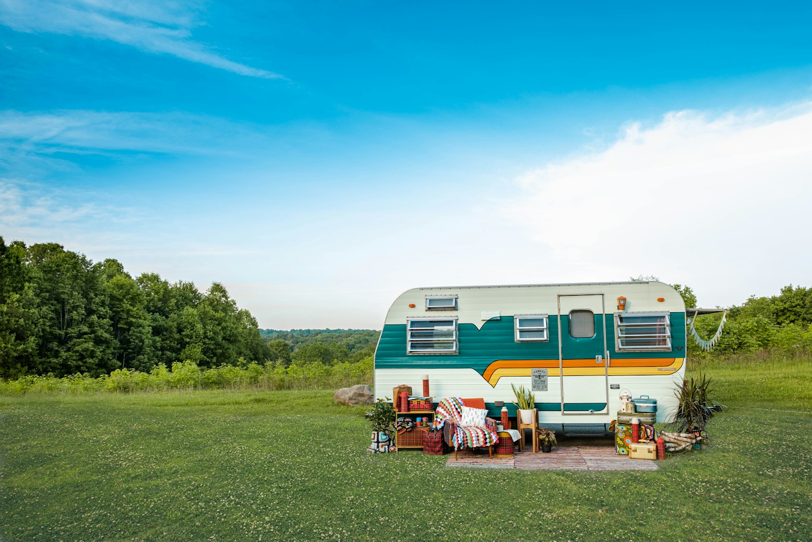 Retro camper trailer parked in an open field, set up for a weekend stay
